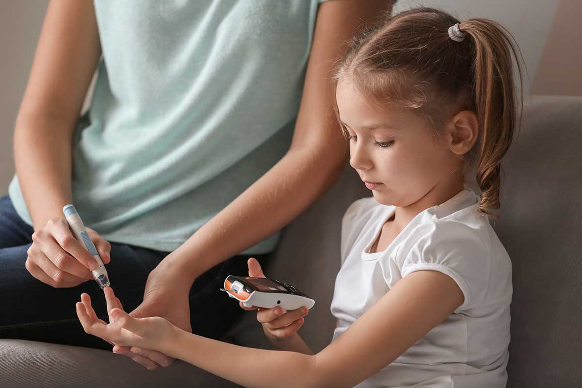 diabetic child checking blood sugar with mom