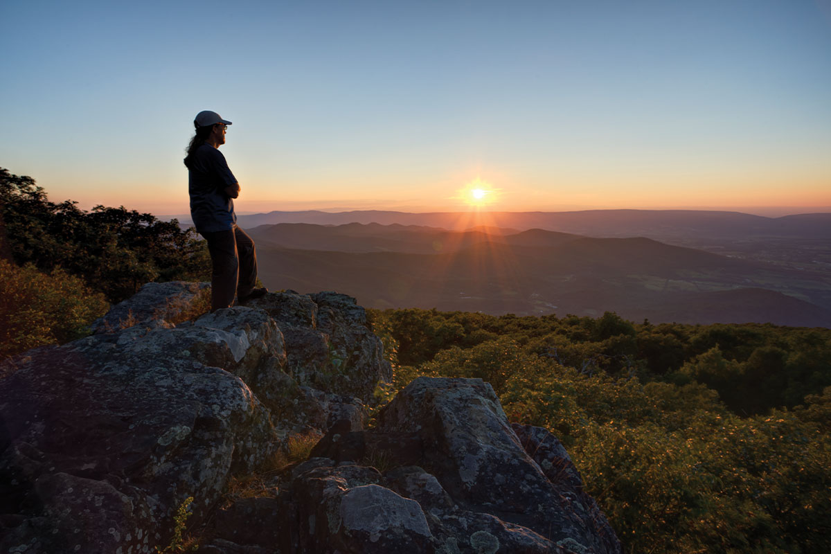 Person standing at top of Blackrock Summit at sunset