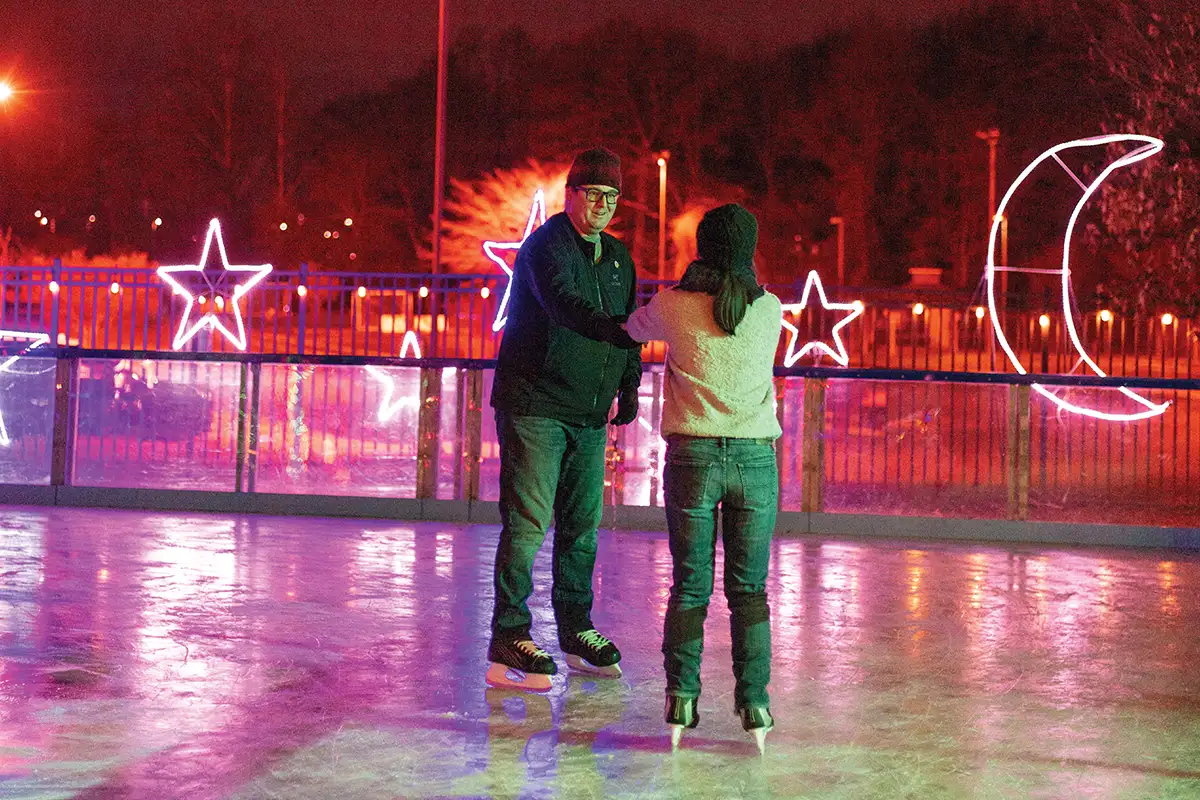 Guests ice skating surrounding by holiday light displays at Ice and Lights at Cameron Run Park.