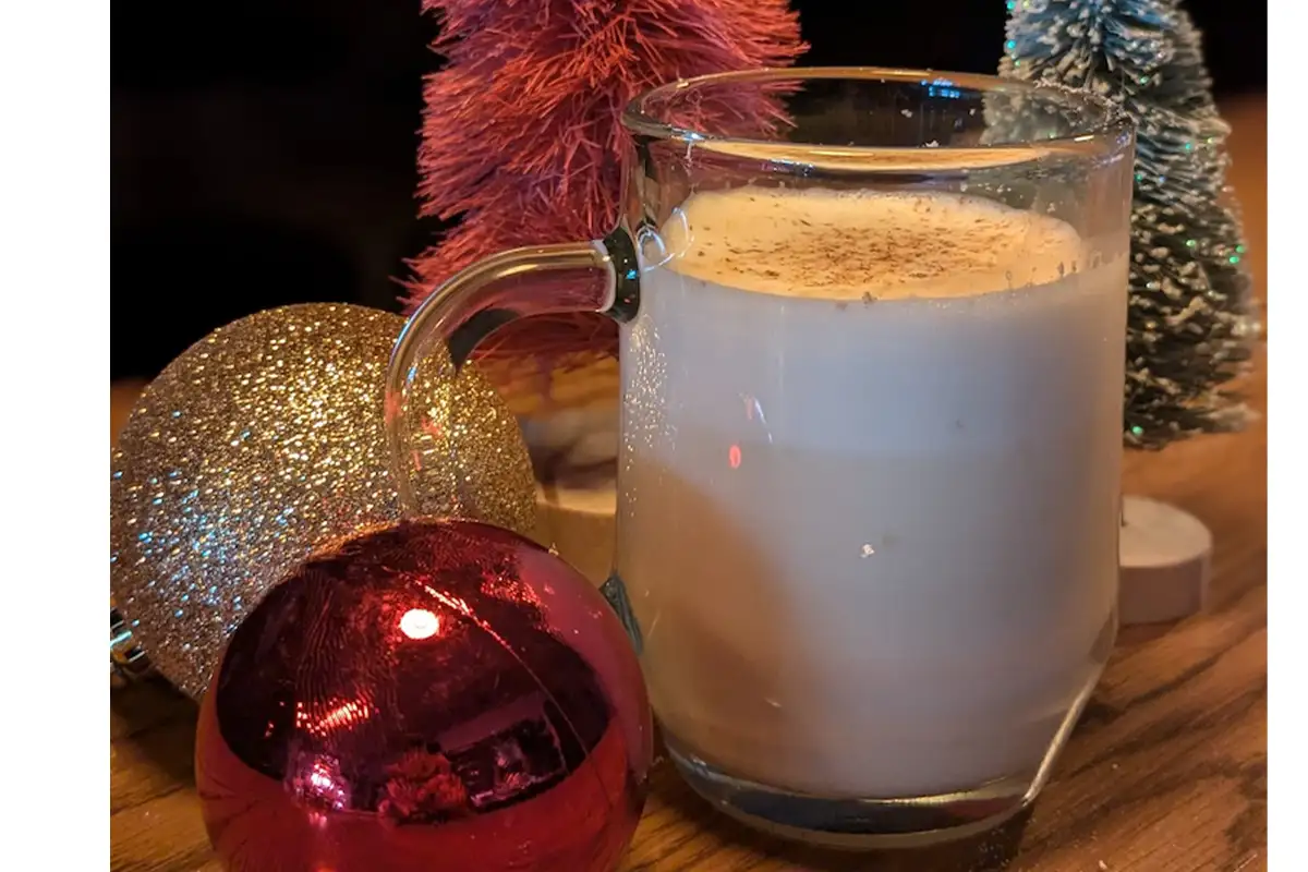 a cup of eggnog surrounded by ornaments and holiday decorations