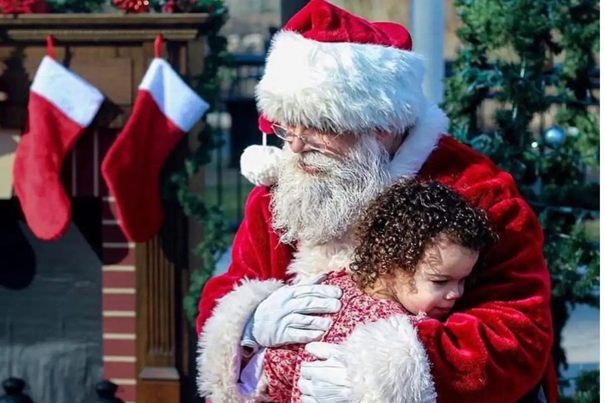 Santa hugs a young girl at a holiday event