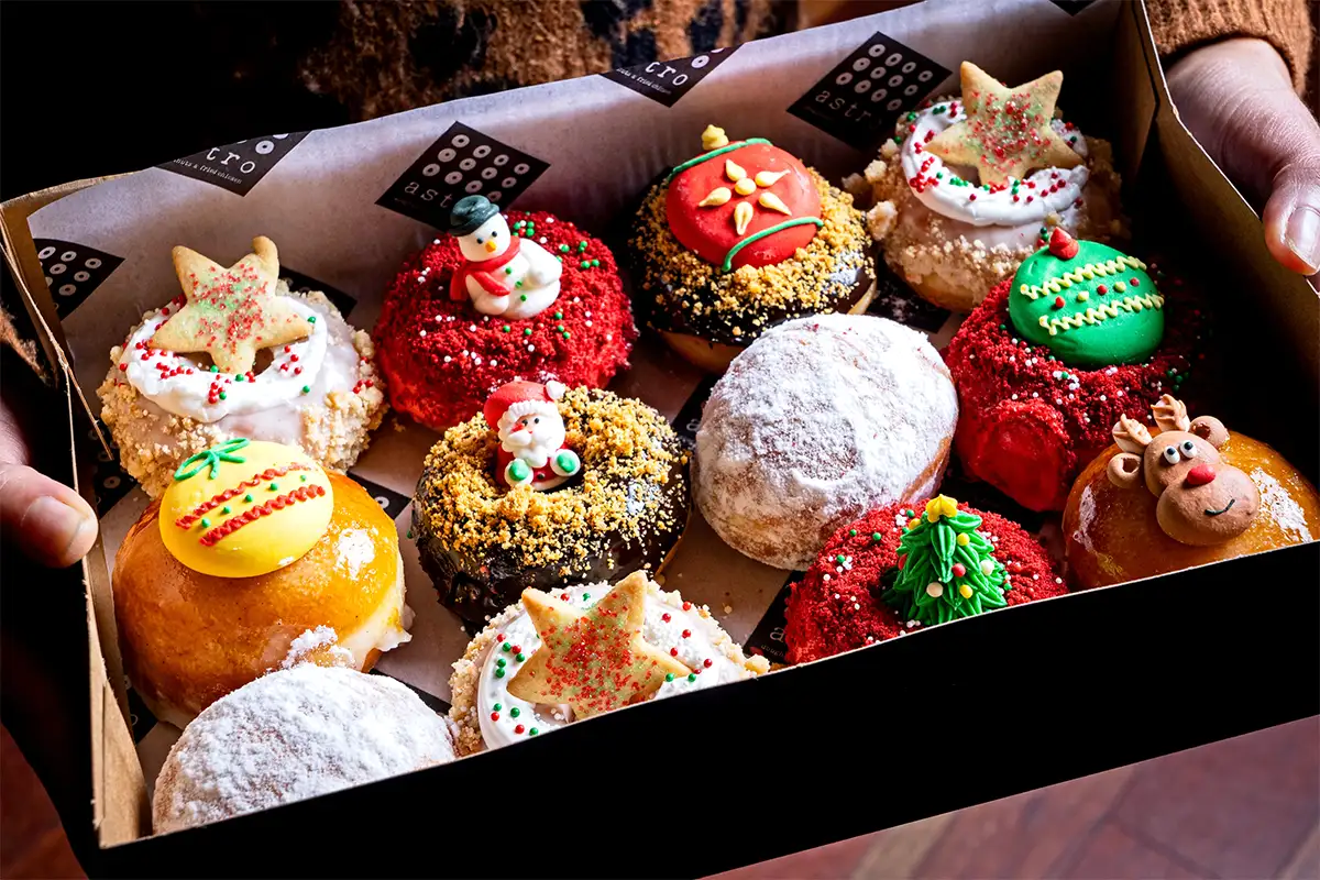 a dozen doughnuts in a box decorated for the Christmas holiday