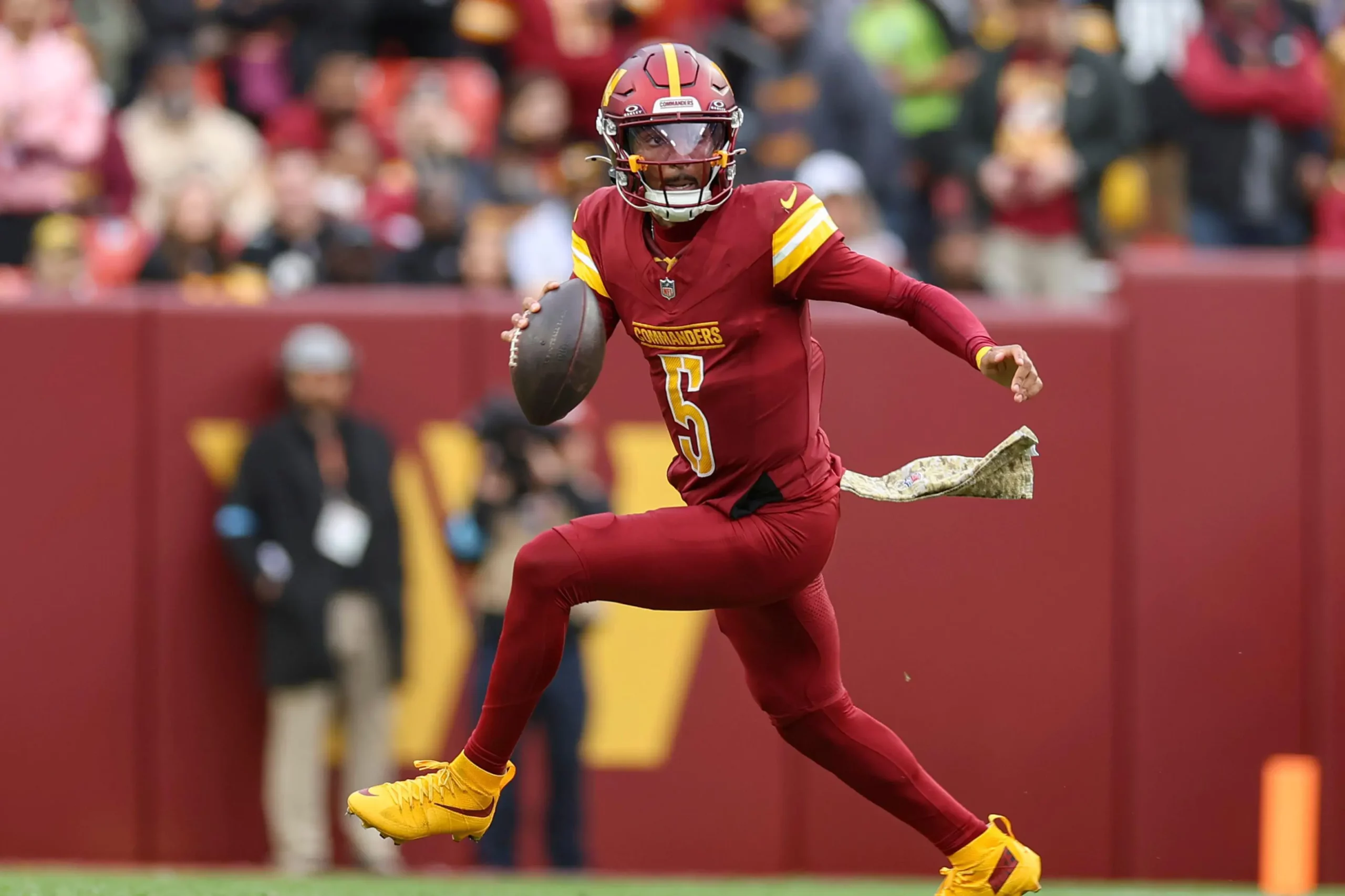 Washington Commanders quarterback Jayden Daniels (5) scrambles out of the pocket and looks for an open receiver during an NFL game