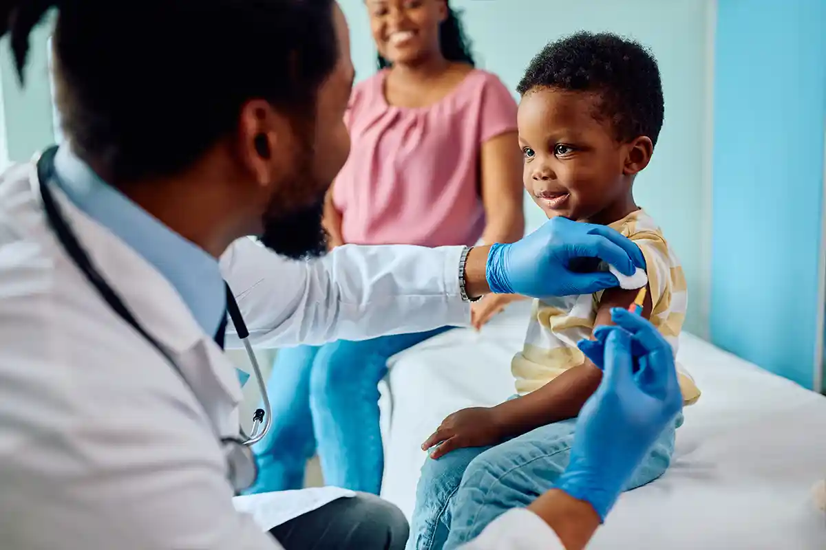 child getting vaccine by doctor with mom in background