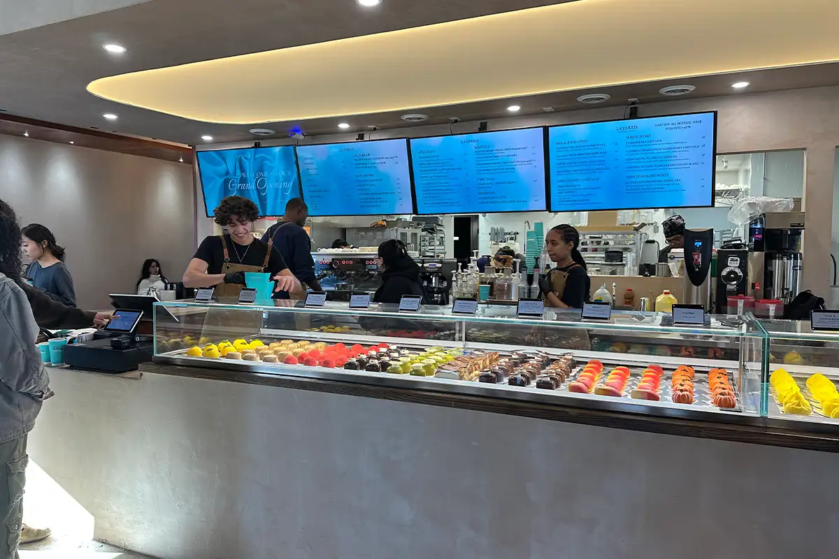 Layered employees stand behind the pastry case