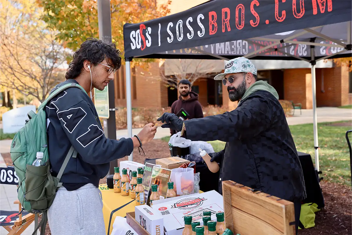 a student samples SOSS hot sauce at a booth on the GMU Fairfax campus