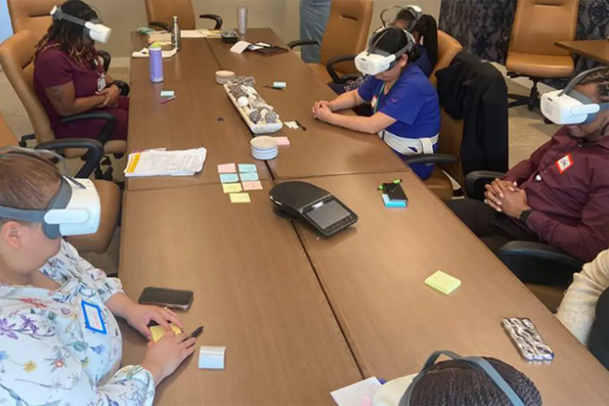 caregivers sit around table wearing virtual reality headsets